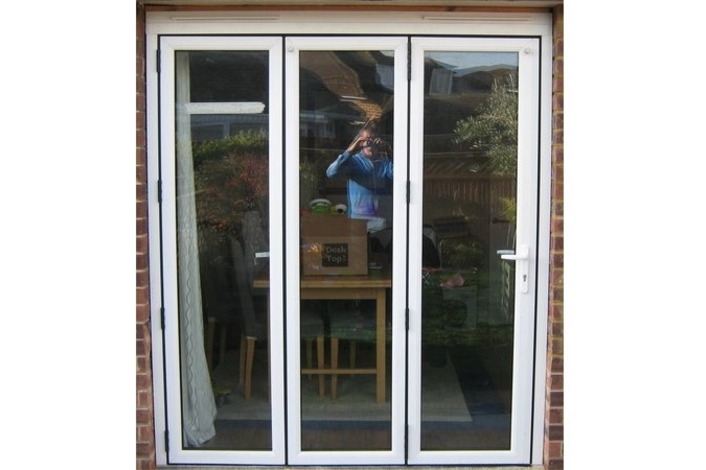 External view of a Timberlook PVCu 3 panel folding sliding door showing the traffic door on the right.  All 3 panels of this bifold will fold and slide to the left.