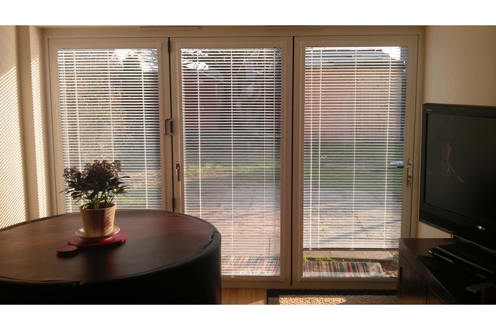 Internal view of a white Visofold 1000 aluminium bifold door with blinds fitted by customer.