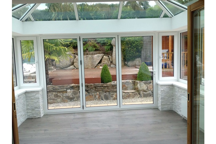 White aluminium bifold doors fitted in a conservatory also supplied by us.